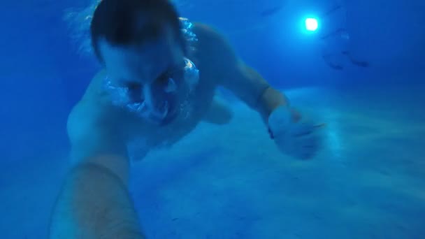 Young man is swimming under the water in the pool - Záběry, video