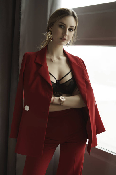 Una mujer seria con un traje rojo. elegante mujer joven con pendientes de oro vintage. top de encaje debajo de la chaqueta. modelo de moda rubia
 - Foto, imagen
