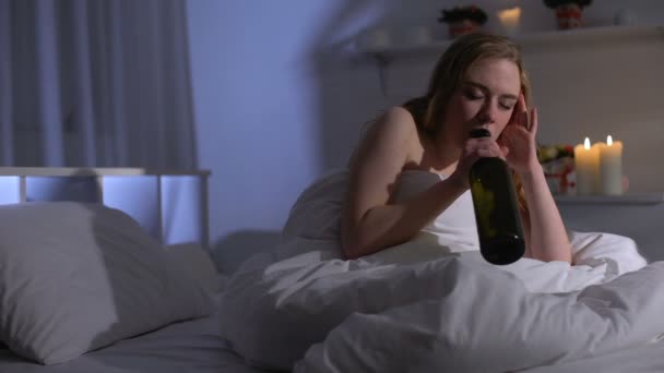 Young woman suffering major depression, drinking wine in bed, alcohol addiction - Filmati, video