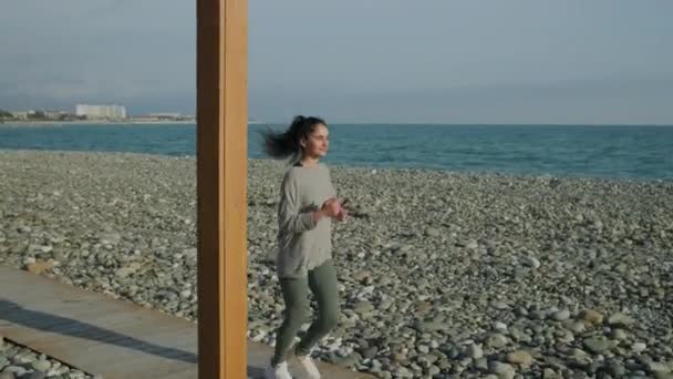 Tiener meisje is joggen alleen op zee kust in zonnige dag - Video