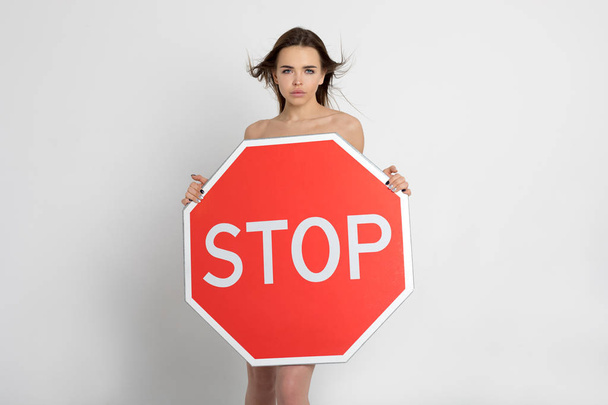 Sexy young woman holding a big red stop sign. - Zdjęcie, obraz
