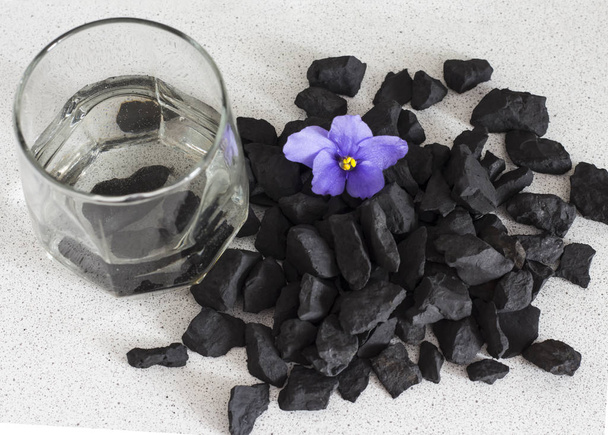 Shungite stones in a glass of water to clean and recharge water ,close-up view from above - Photo, Image