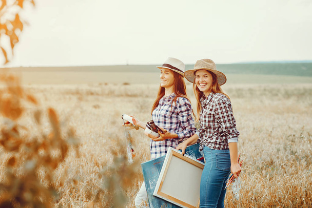 Two beautiful girls drawing in a field - Foto, Imagen