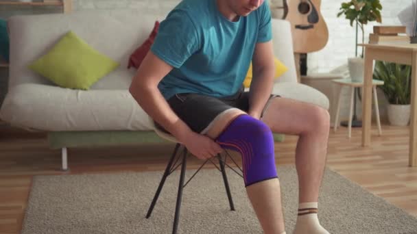 Sportler bereitet sich mit Verband am Knie auf das Training vor - Filmmaterial, Video