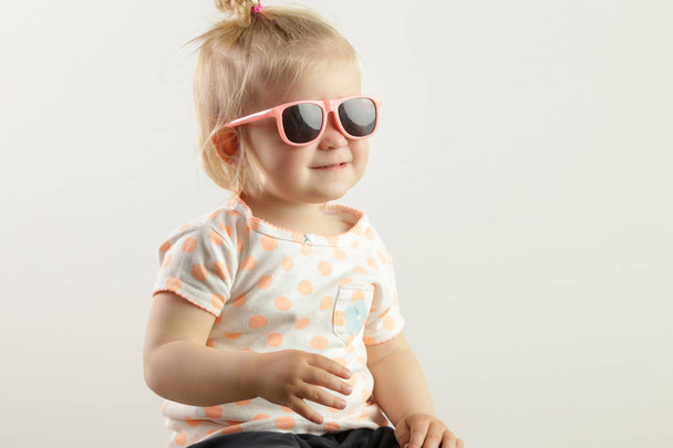 ピンクのサングラスを持つ愛らしい女の赤ちゃんのスタジオショット - 写真・画像