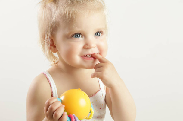 Studio muotokuva ihana blondi hymyilevä vauva tyttö näyttää hampaansa sormella
  - Valokuva, kuva