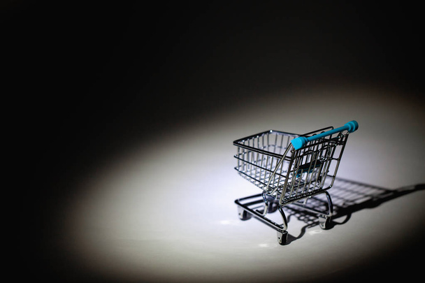 Spotlight and shopping trolley in the dark room. - Foto, imagen
