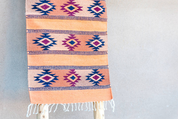 Tradycyjny południowo-zachodni dywan na wyświetlaczu przez Adobe House Wall, Taos, Nowy Meksyk, USA - Zdjęcie, obraz