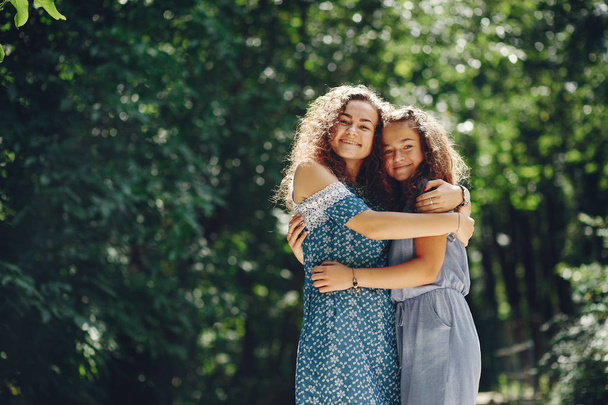 Two cute sisters in a summer park - Fotó, kép