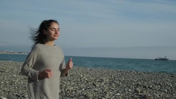 Vrouwelijke Runner is trainen op de kust in zonnige ochtend, wenden tot camera - Video