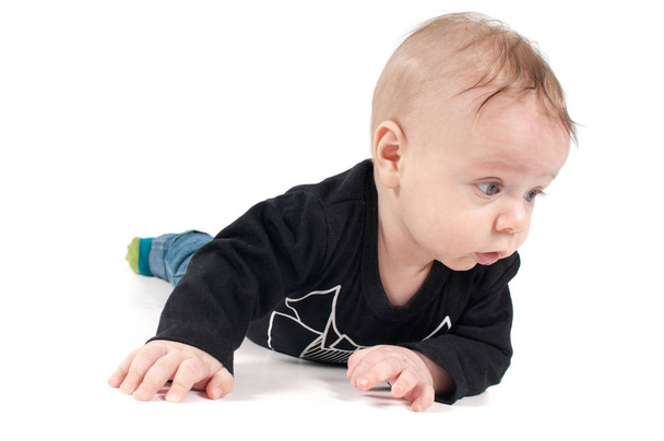 Shot of little baby in black top lying on white background - Фото, зображення