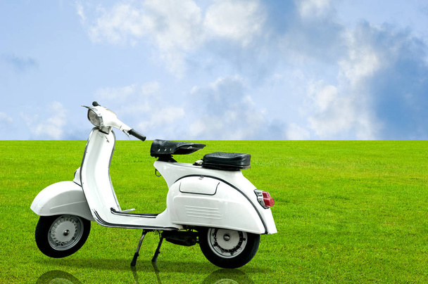 White vintage motorbike parking on the grass with nice cloudy sky - Zdjęcie, obraz