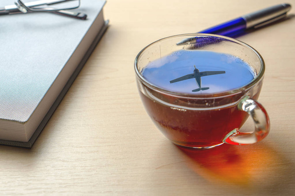 Una tazza di tè con un riflesso dell'aereo nel cielo sulla scrivania dell'ufficio
 - Foto, immagini