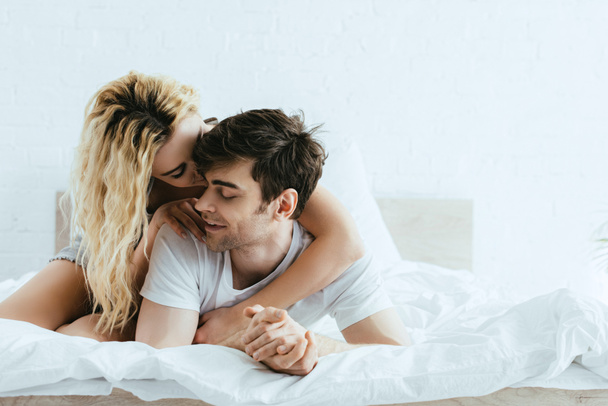 happy blonde girl hugging handsome boyfriend lying on bed  - Foto, immagini