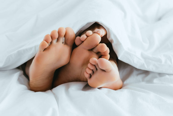 cropped view of girlfriend and boyfriend with barefoot lying in bed  - Zdjęcie, obraz