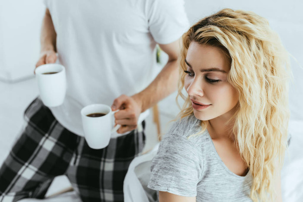cropped view of man holding cups with coffee near attractive blonde woman  - Photo, Image