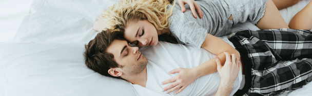 panoramic shot of happy couple hugging while lying on bed  - Fotografie, Obrázek