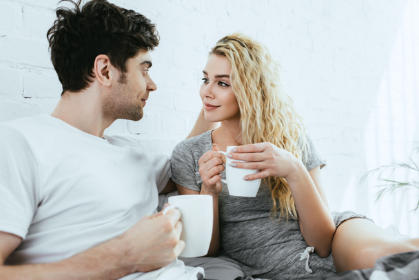happy handsome man looking at attractive blonde girl holding cup  - Photo, image