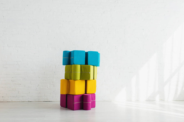 colorful puzzle shape poufs near white brick wall at home  - Foto, Imagem