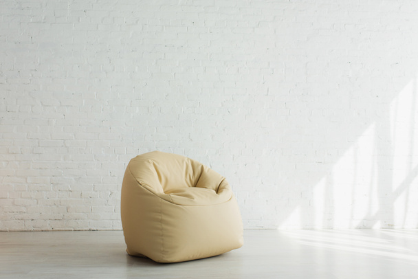 sunlight near beige bean bag chair near brick wall in modern home  - Foto, imagen