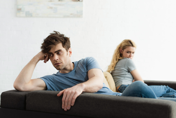 selective focus of upset man sitting near blonde woman after quarrel  - Φωτογραφία, εικόνα