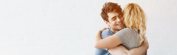 panoramic shot of happy man smiling while hugging blonde girl  - Photo, Image