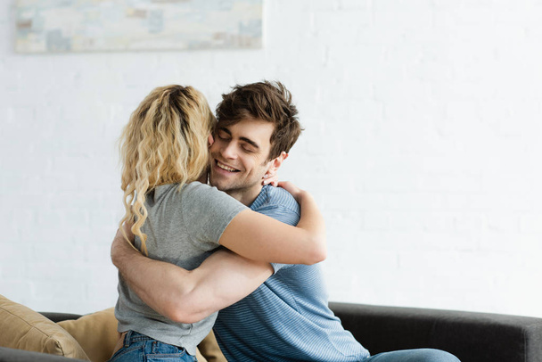 happy man smiling while hugging blonde girl at home  - Фото, изображение