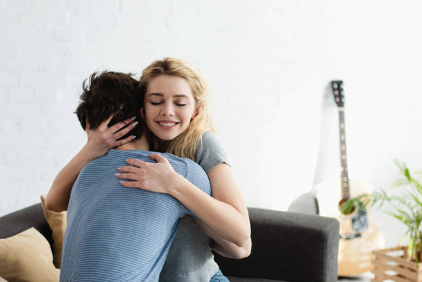 happy young woman smiling while hugging boyfriend at home  - Fotoğraf, Görsel
