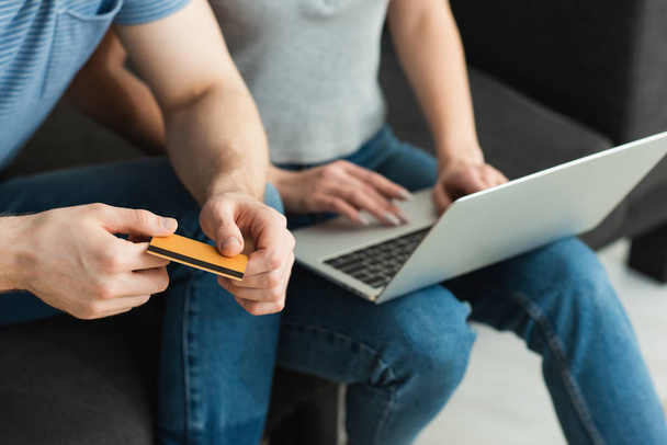 cropped view of man holding credit card near young woman using laptop - Φωτογραφία, εικόνα