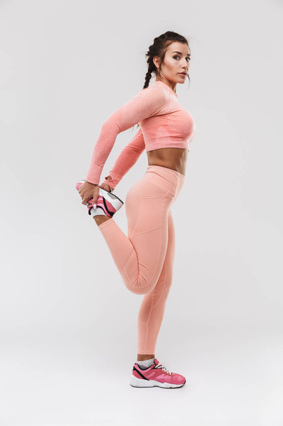 Young amazing strong sports fitness woman posing isolated over white wall background make exercises. - 写真・画像