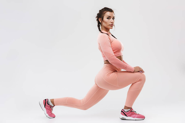 junge erstaunliche starke Sport Fitness Frau posiert isoliert über weiße Wand Hintergrund machen Übungen. - Foto, Bild