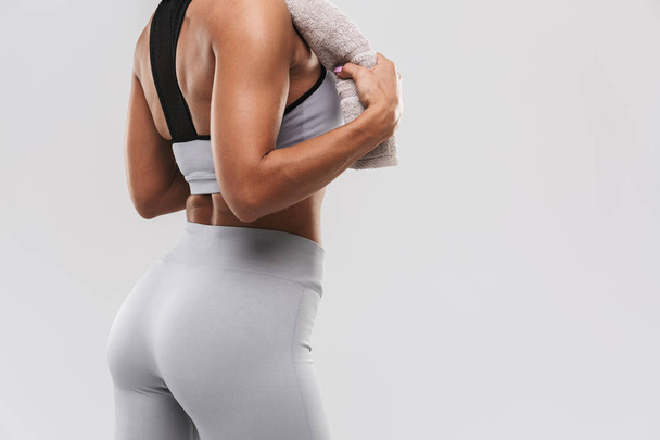 Beautiful young amazing strong sports fitness woman posing isolated over white wall background holding towel. - 写真・画像