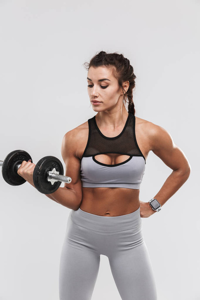 Beautiful young amazing strong sports fitness woman posing isolated over white wall background make exercises with dumbbell. - Фото, изображение