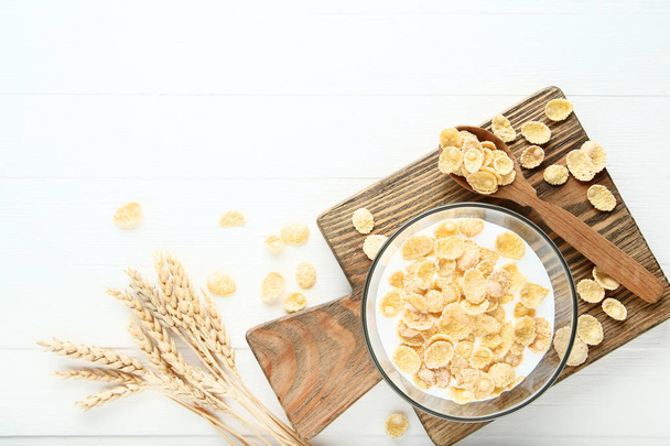 Corn flakes in milk with wheat ears on white wooden table - Foto, Imagen