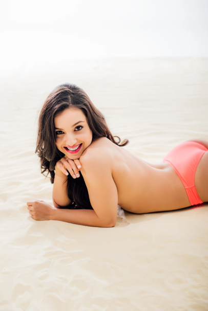 güzel üstsüz Genç kadın kameraya bakarak, gülümseyen ve kumlu plajda rahatlatıcı - Fotoğraf, Görsel