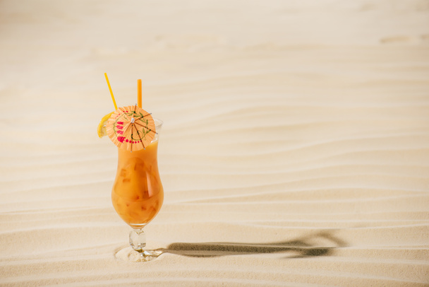 orange cocktail with cocktail umbrella on sandy beach with copy space - Photo, Image