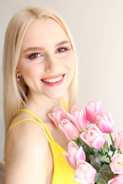 Attractive young woman posing over grey background with flowers. - Фото, зображення