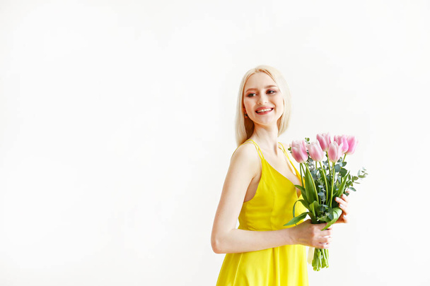 Attractive young woman posing over grey background with flowers. - Fotoğraf, Görsel