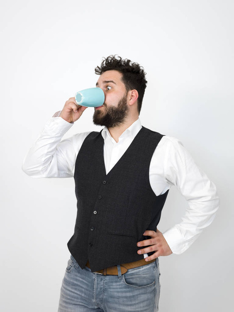 handsome man with black beard posing with turquoise coffee cup in front of white background   - Foto, afbeelding