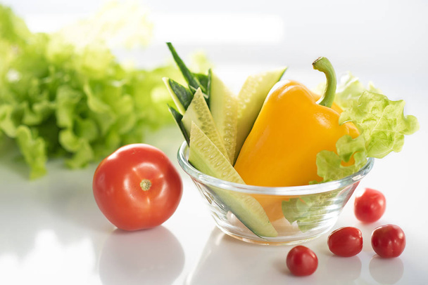 A set of fresh vegetables on a white plate, for the preparation of vegetable vegetarian salad. The background is white - Valokuva, kuva