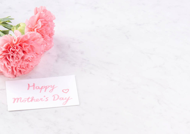 Copy space, close up, mock up, clipping path. Mothers day wording concept design. Beautiful fresh blooming baby pink color carnations isolated on bright marble background. - Foto, immagini