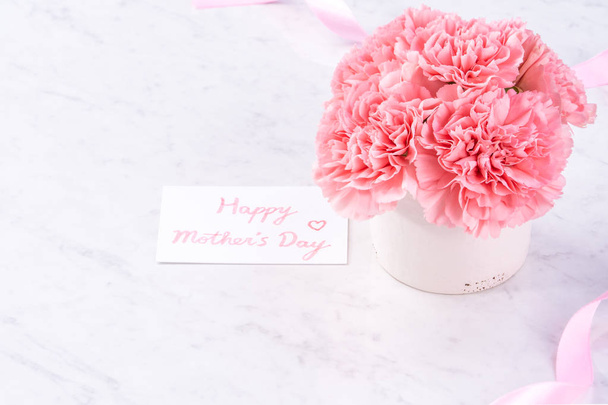 Copy space, close up, mock up, clipping path. Mothers day wording concept design. Beautiful fresh blooming baby pink color carnations isolated on bright marble background. - 写真・画像