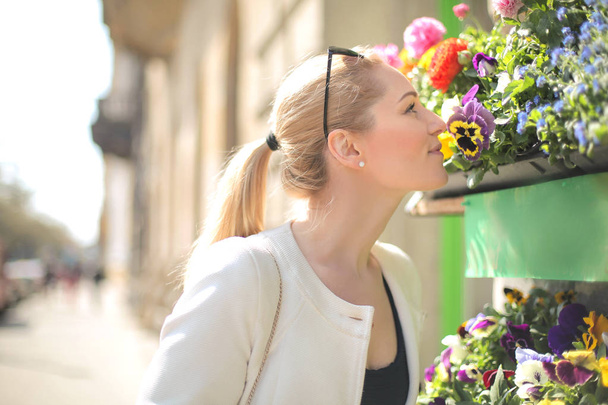 νεαρή ξανθιά γυναίκα μυρίζοντας λουλούδια - Φωτογραφία, εικόνα