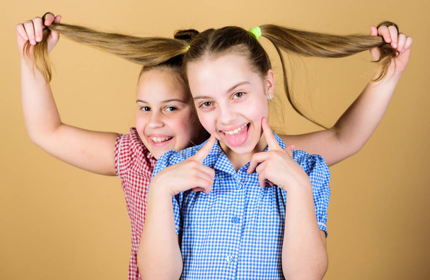 Adding care to her hair. Playful little girl keeping long hair of adorable baby. Cute happy kid with fashionable hair ponytails. Small child smiling with blond hair - Fotó, kép