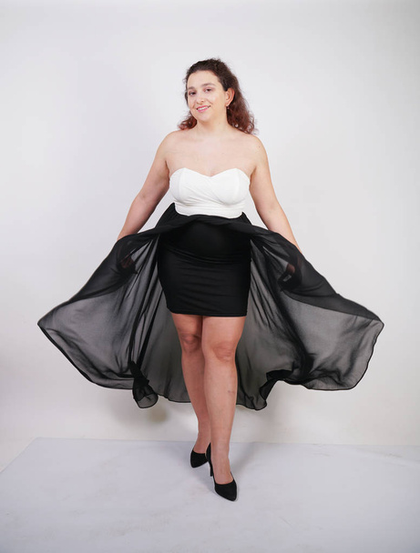 charming chubby happy woman standing in flying evening dress on white studio background alone - Foto, Imagem