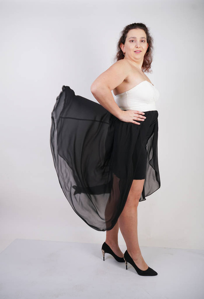 charming chubby happy woman standing in flying evening dress on white studio background alone - Photo, Image