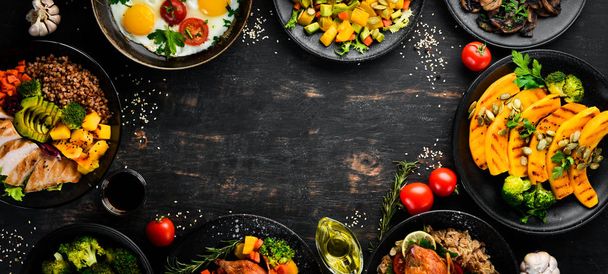 Assortment of food. Salad, avocado, quail, mushrooms, pumpkin. On a black background. Top view. Free space for your text. - 写真・画像