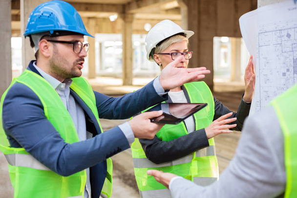 Team of young architects discussing and arguing during a meeting on a construction site - Photo, Image
