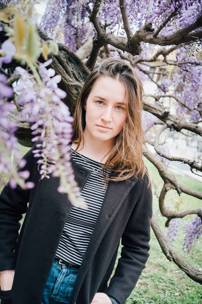 Portrait of a cute teenage girl outdoors near a blooming wisteria - Foto, Imagen