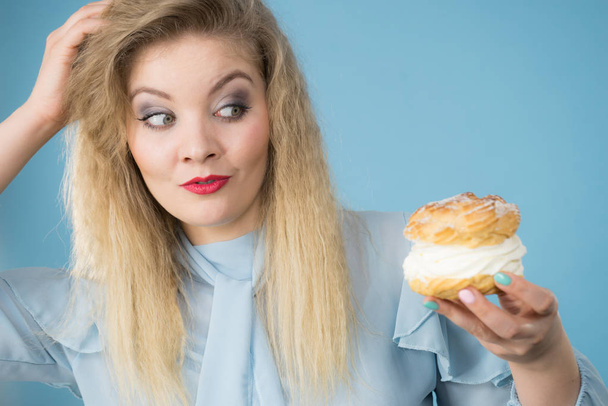 Funny woman holds cream puff cake - Фото, изображение